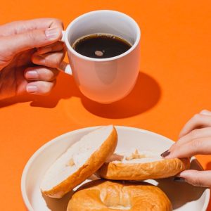 person holding white ceramic mug with brown liquid